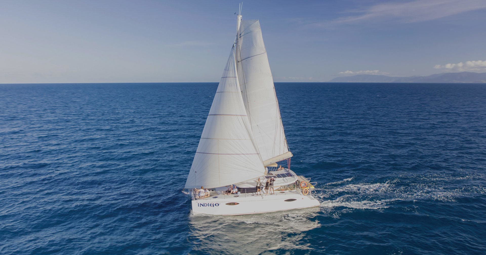 Catamaran sailing on open ocean, blue sea and clear sky