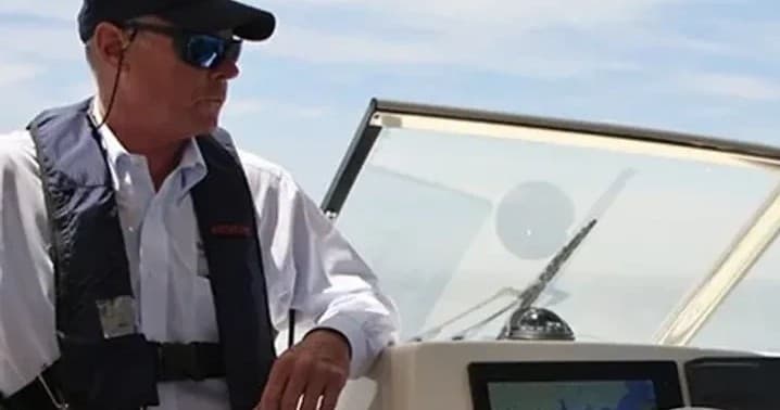 Boat captain steering helm on open water during day excursion