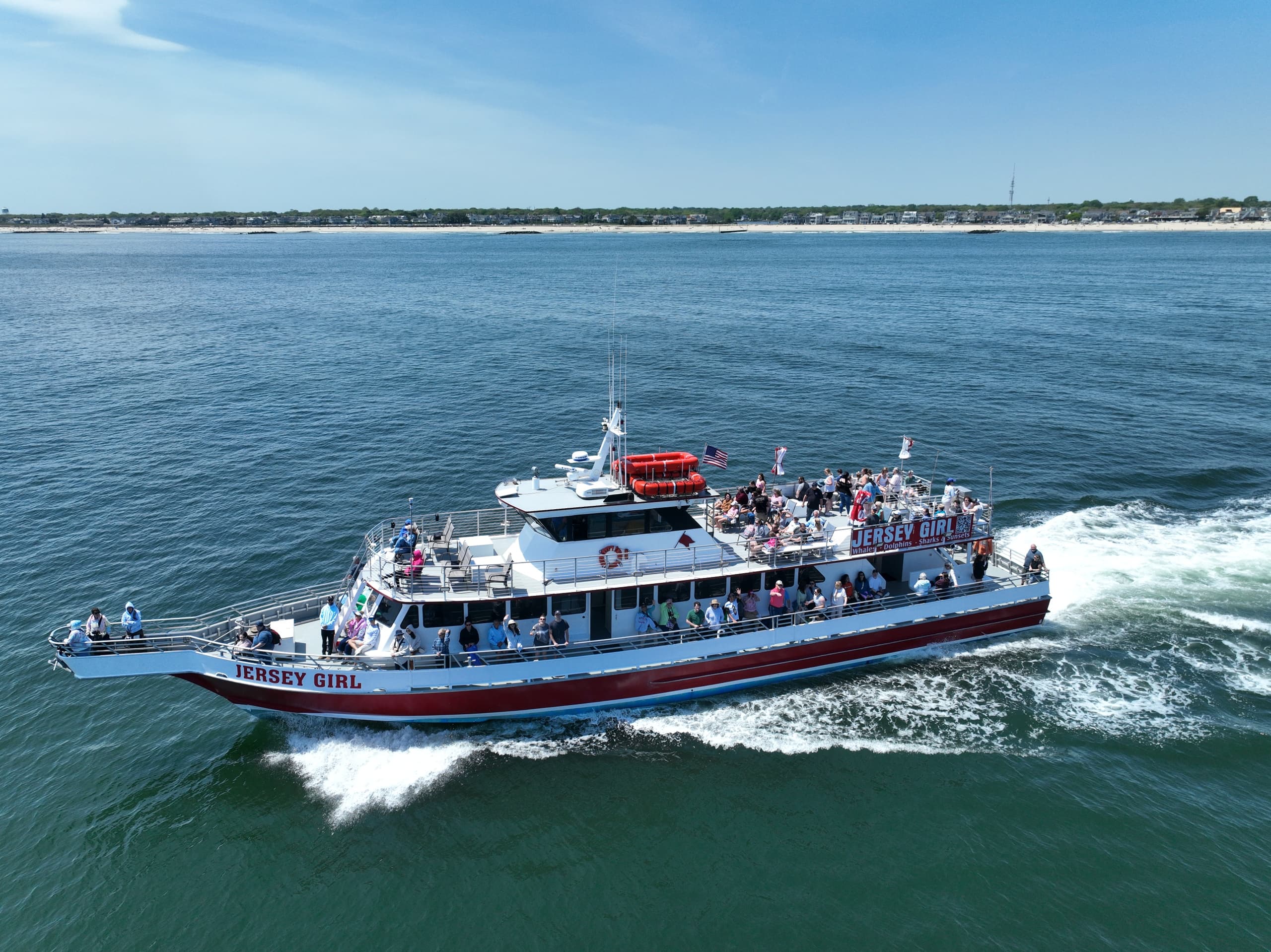 Crowded whale-watch tour boat filled with passengers near coast