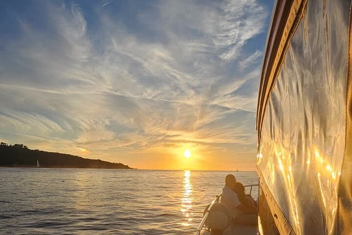 Golden sunset reflecting off yacht hull during coastal cruise, Italy