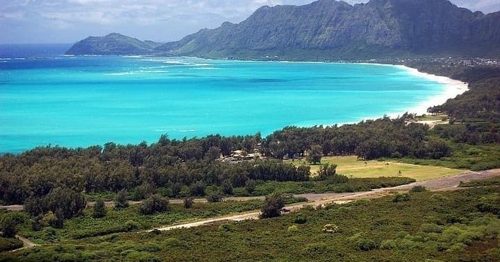 Aerial tropical bay with turquoise water and green coastal ridge
