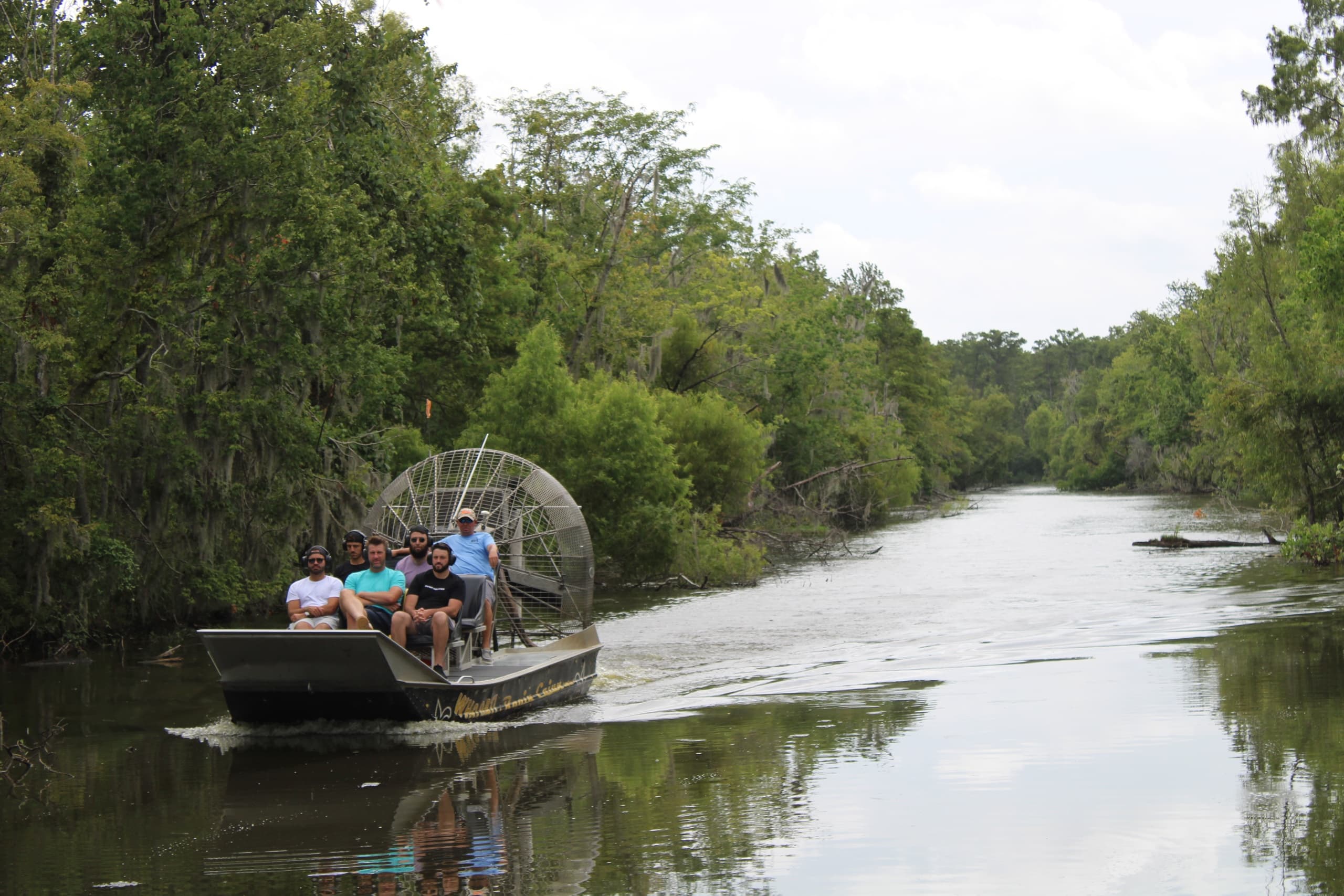 Airboat gliding down cypress-lined river on guided bayou tour