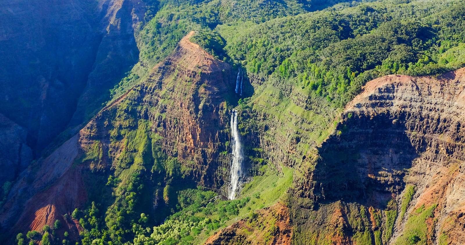 Scenic Waimea Canyon waterfall and rugged cliffs, Kauai aerial