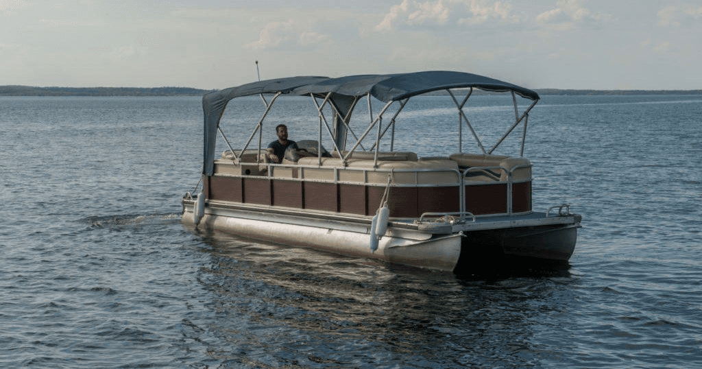 Pontoon boat cruising on lake with canopy, calm waters