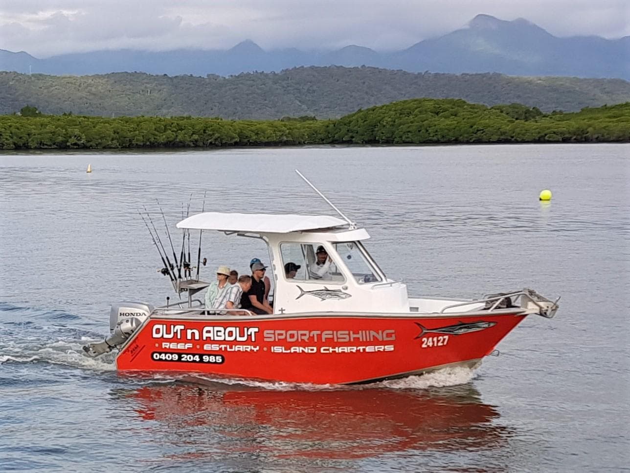 Sportfishing charter cruising coastal waters with mountain backdrop
