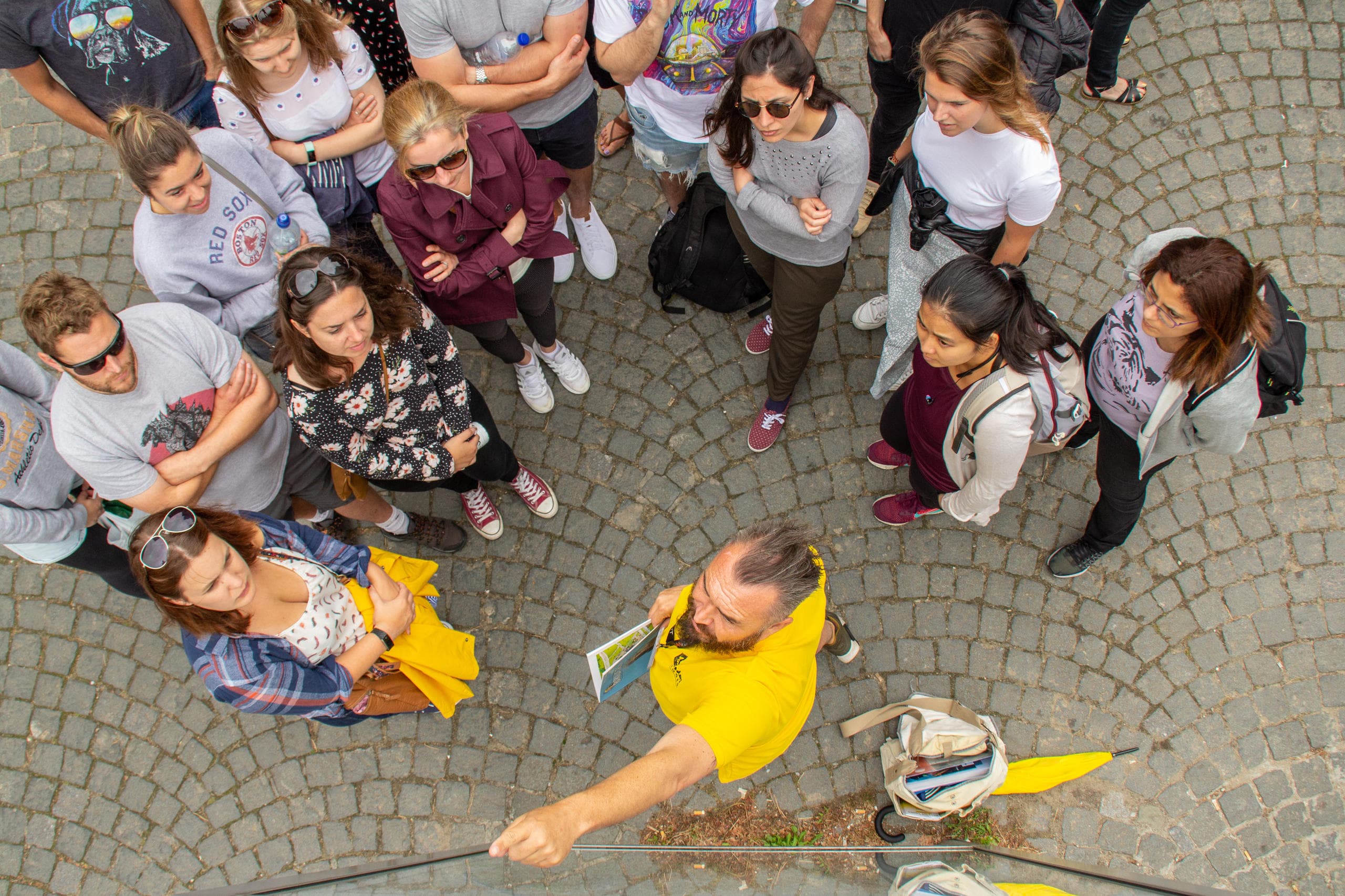 Overhead view of guided walking tour group on cobblestone plaza