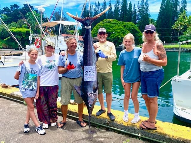 Anglers posing with giant blue marlin at tropical marina dock