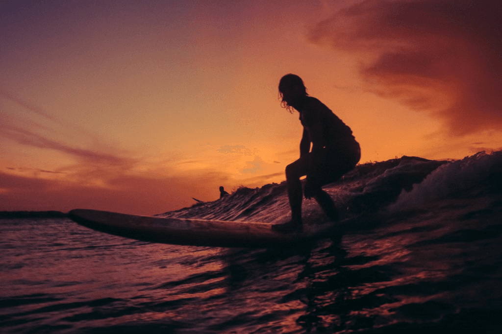 Surfer silhouetted riding a wave at sunset on the ocean