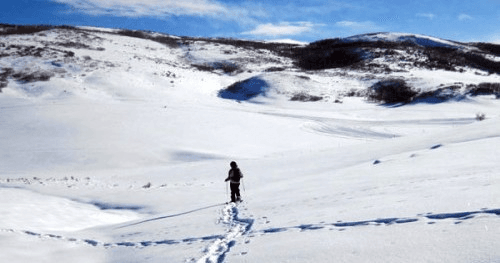 Solo hiker trekking across snowy plains, backcountry winter hike