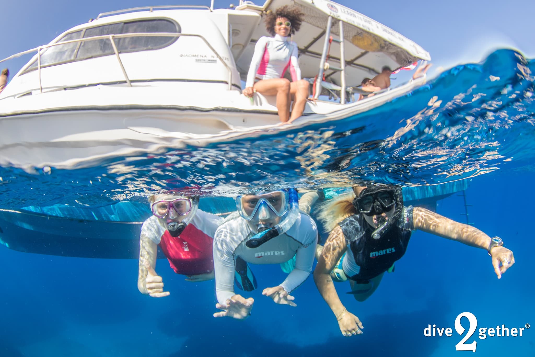 Snorkelers and divers swimming beside a boat in blue ocean