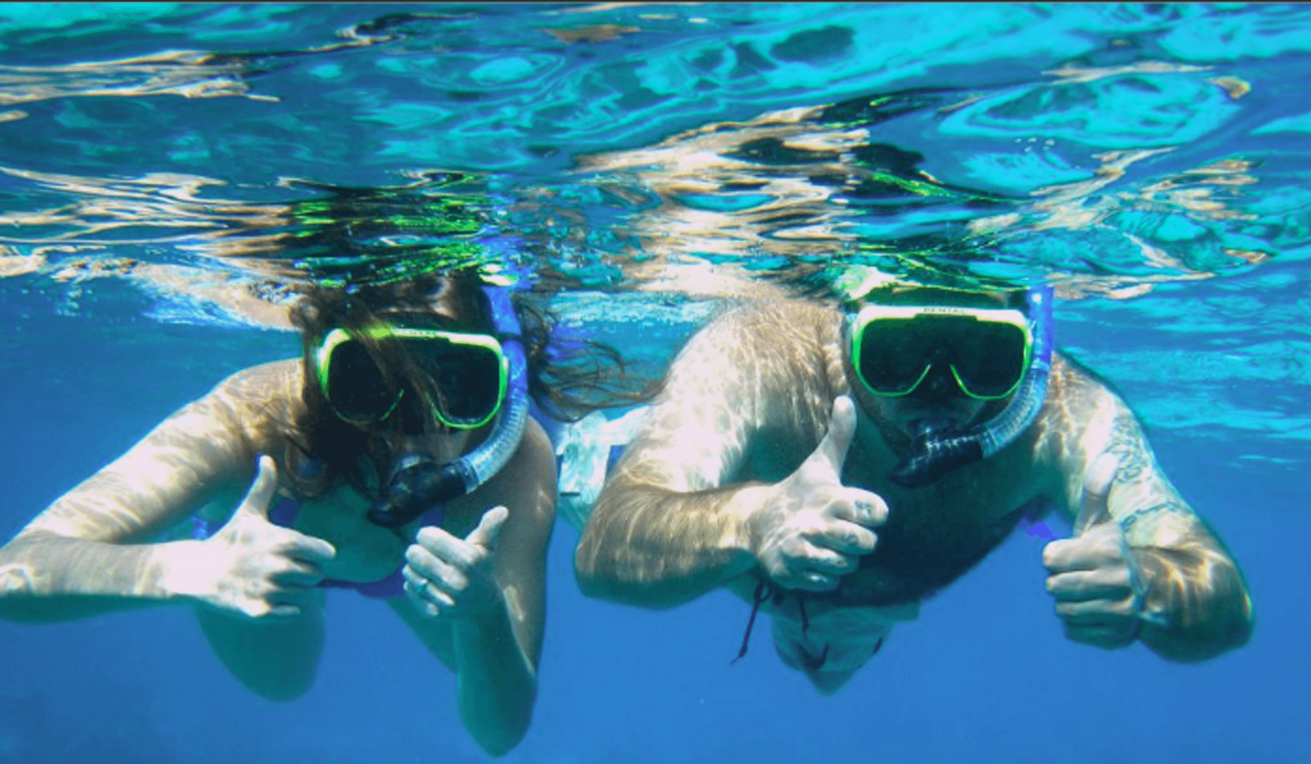 Two snorkelers exploring coral reef in tropical clear water