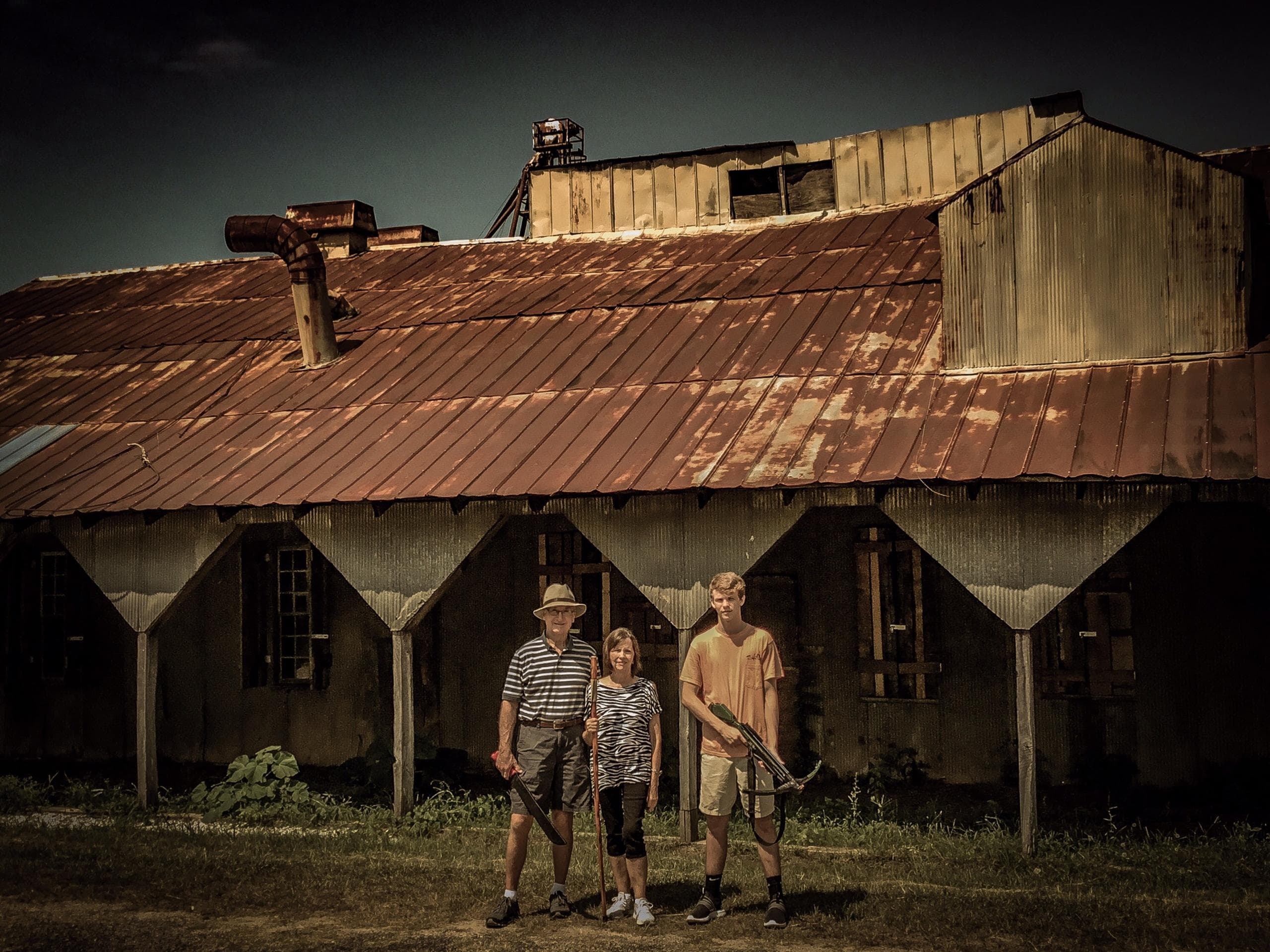 Rustic corrugated-roof building with small outdoor tour party