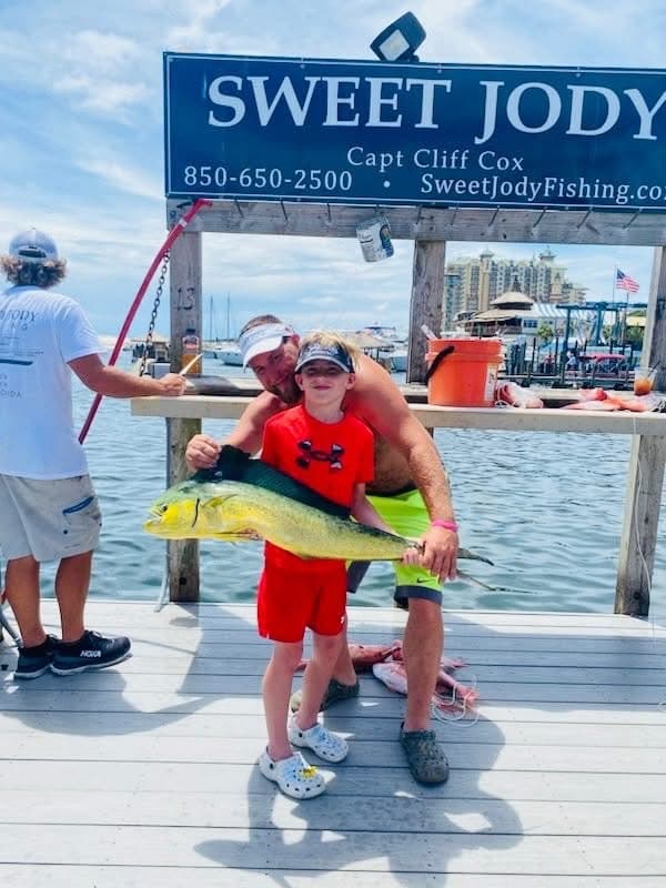 Father and son showing large dolphinfish on marina dock at Sweet Jody