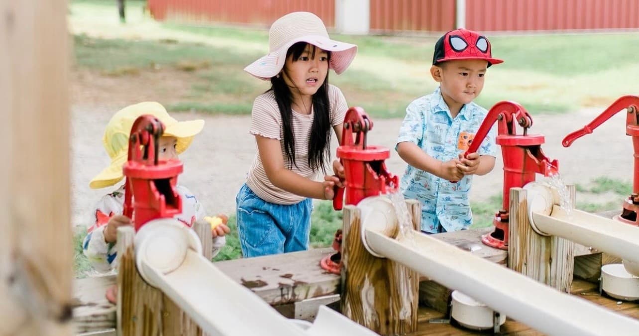 Children playing with hand pumps at orchard outdoor play area