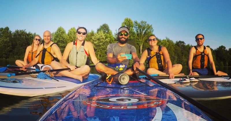 Group kayakers smiling on river paddleboards at sunrise