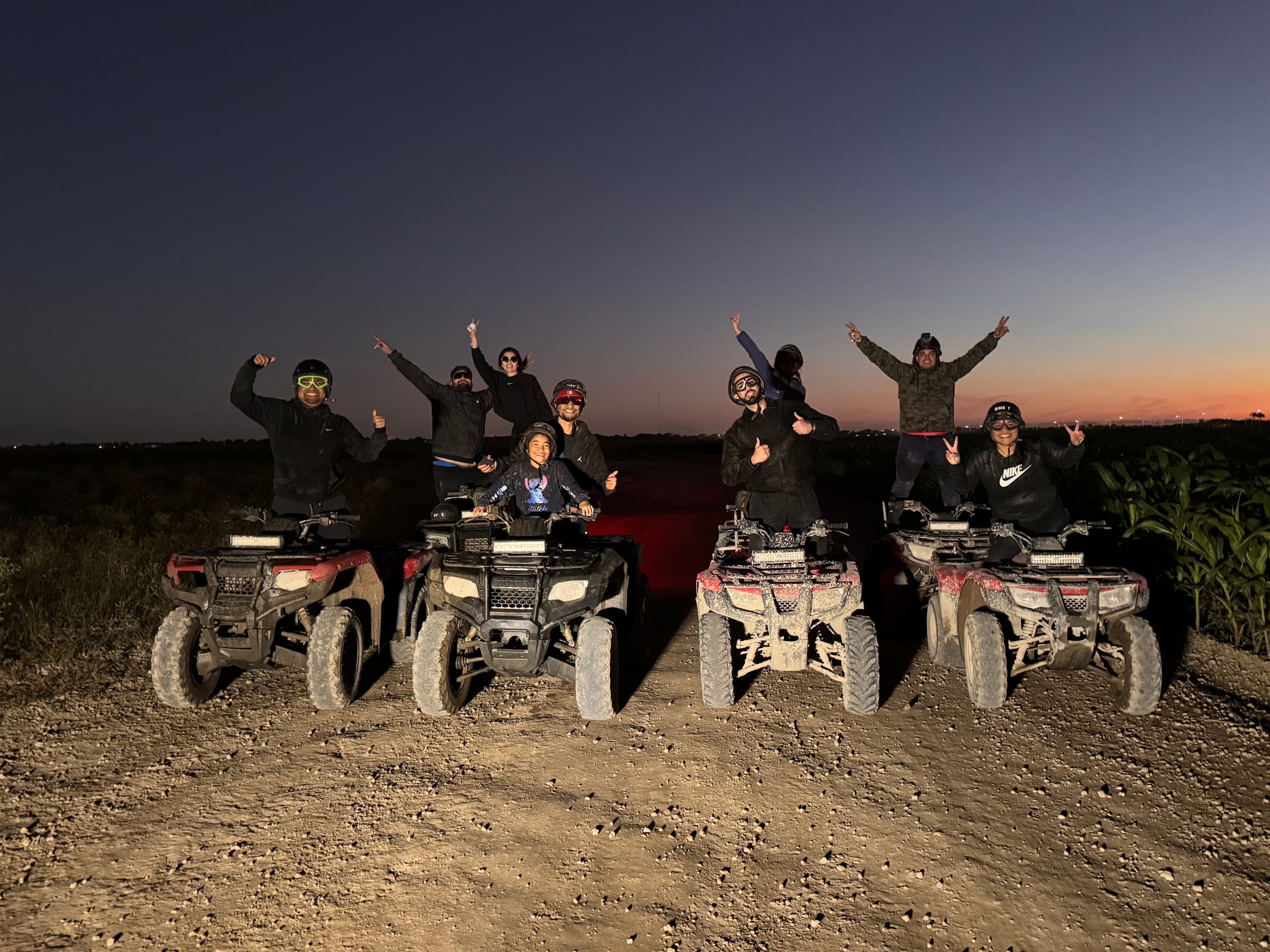 Sunset ATV group ride on dusty trail with riders celebrating