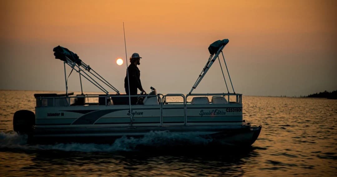 Pontoon boat cruising at sunset on open water