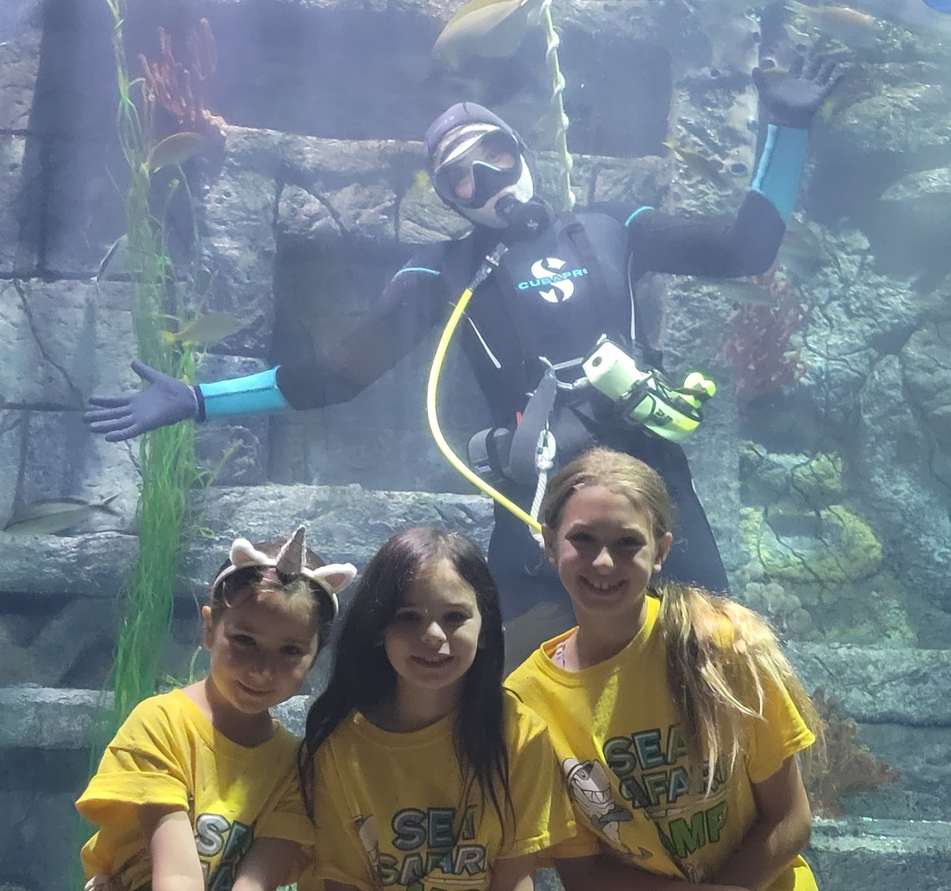 Children watching scuba diver show through aquarium window