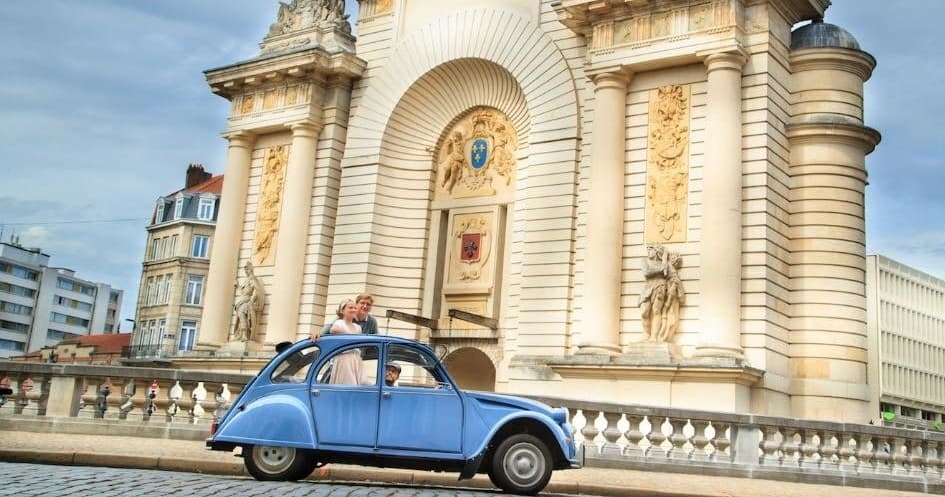 Blue vintage 2CV parked by ornate cathedral facade, city sightseeing
