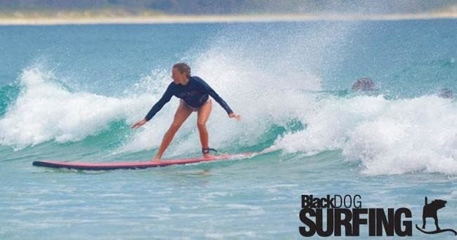 Female surfer riding small wave on a longboard near shore