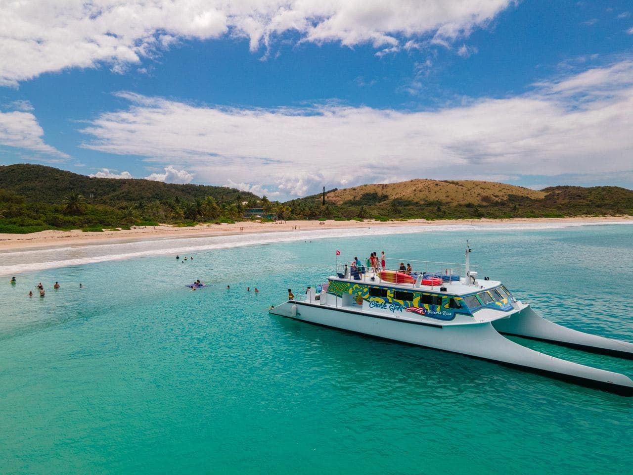 Tour boat anchored in turquoise bay along tropical coastline