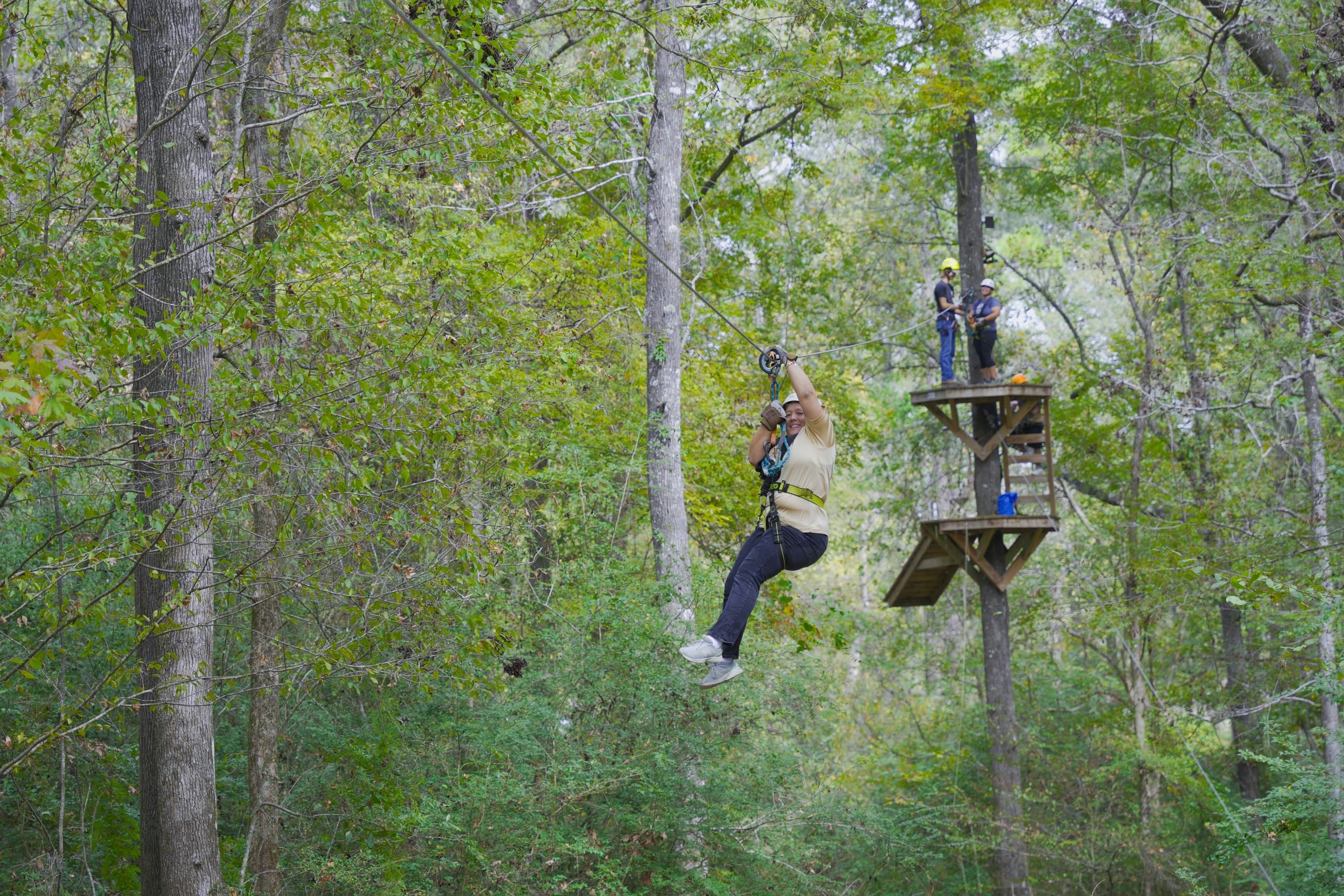 Zipliner gliding through lush forest canopy on outdoor zipline