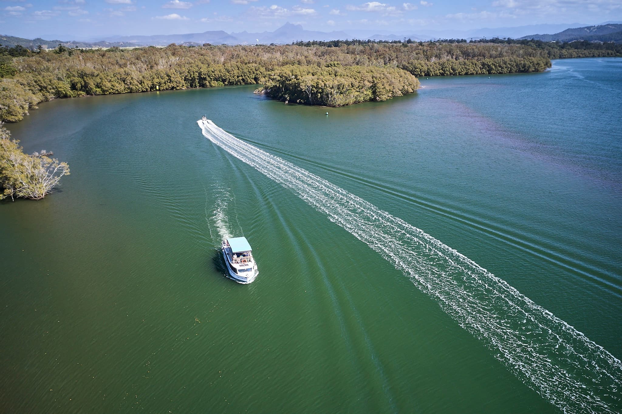 Aerial view of speedboat cutting wake on wide river cruise