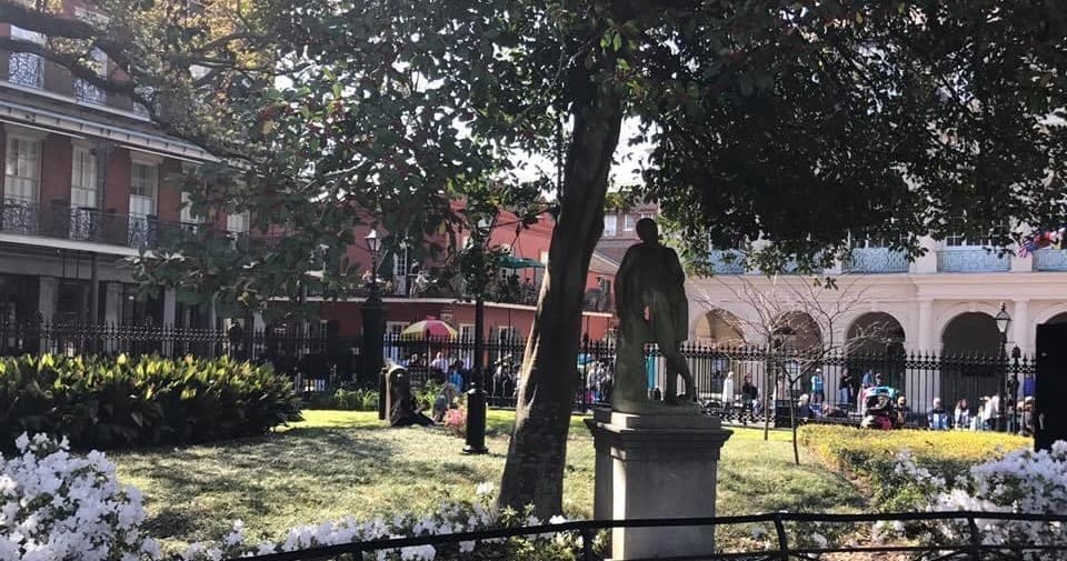 Historic courtyard garden with statue and visitors, outdoor plaza
