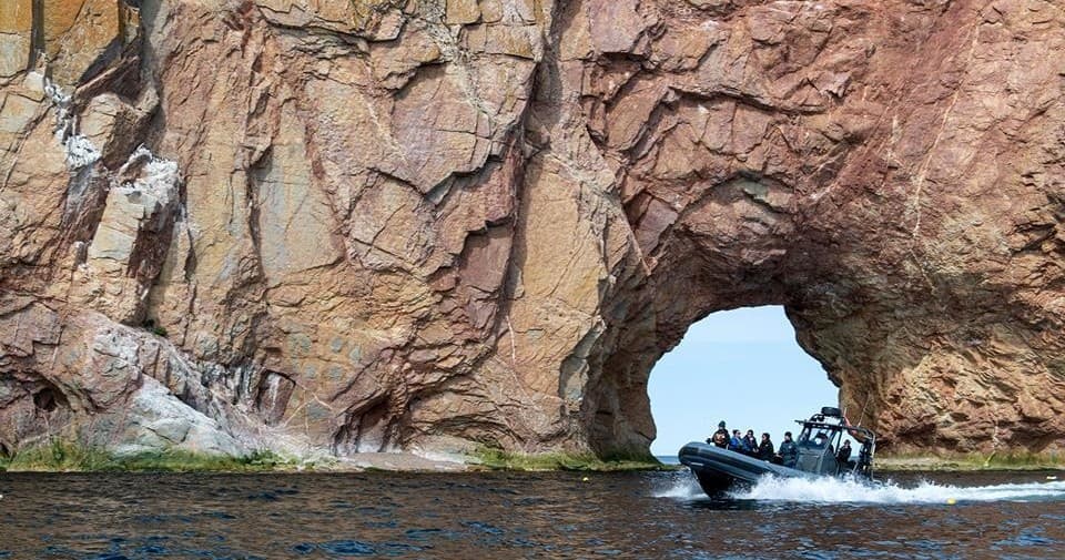 Zodiac boat passing through Perce rock arch on coastal tour