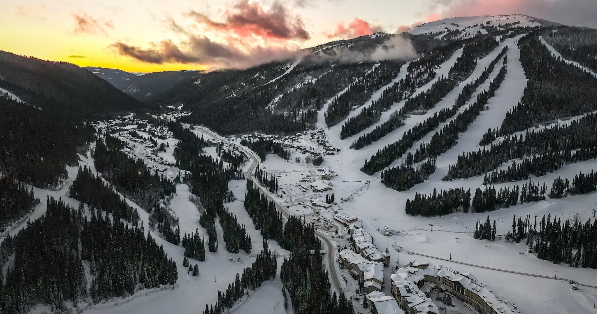Aerial view of snowy ski resort runs at sunrise in mountains