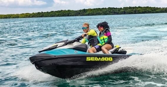 Couple jet skiing near coastal shoreline in turquoise waters