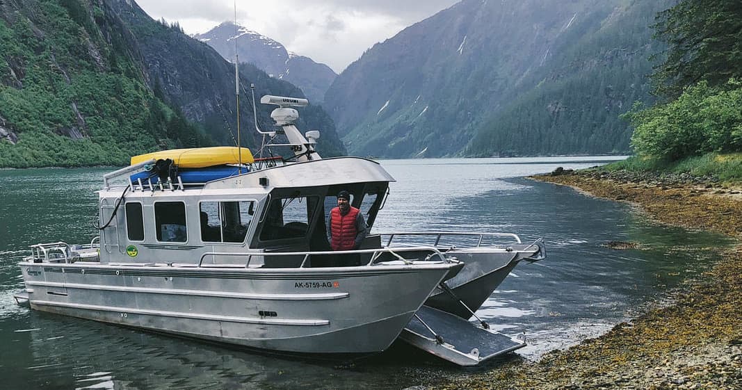 Rigid boat anchored in Alaskan fjord with mountain scenery
