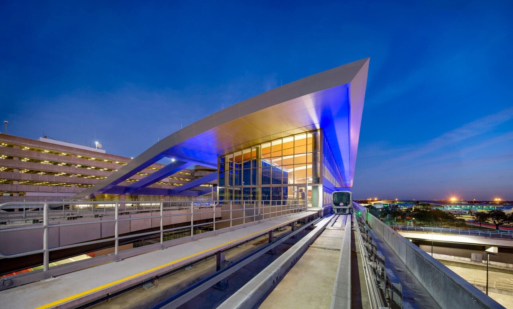 Illuminated airport monorail platform and approach tracks at dusk