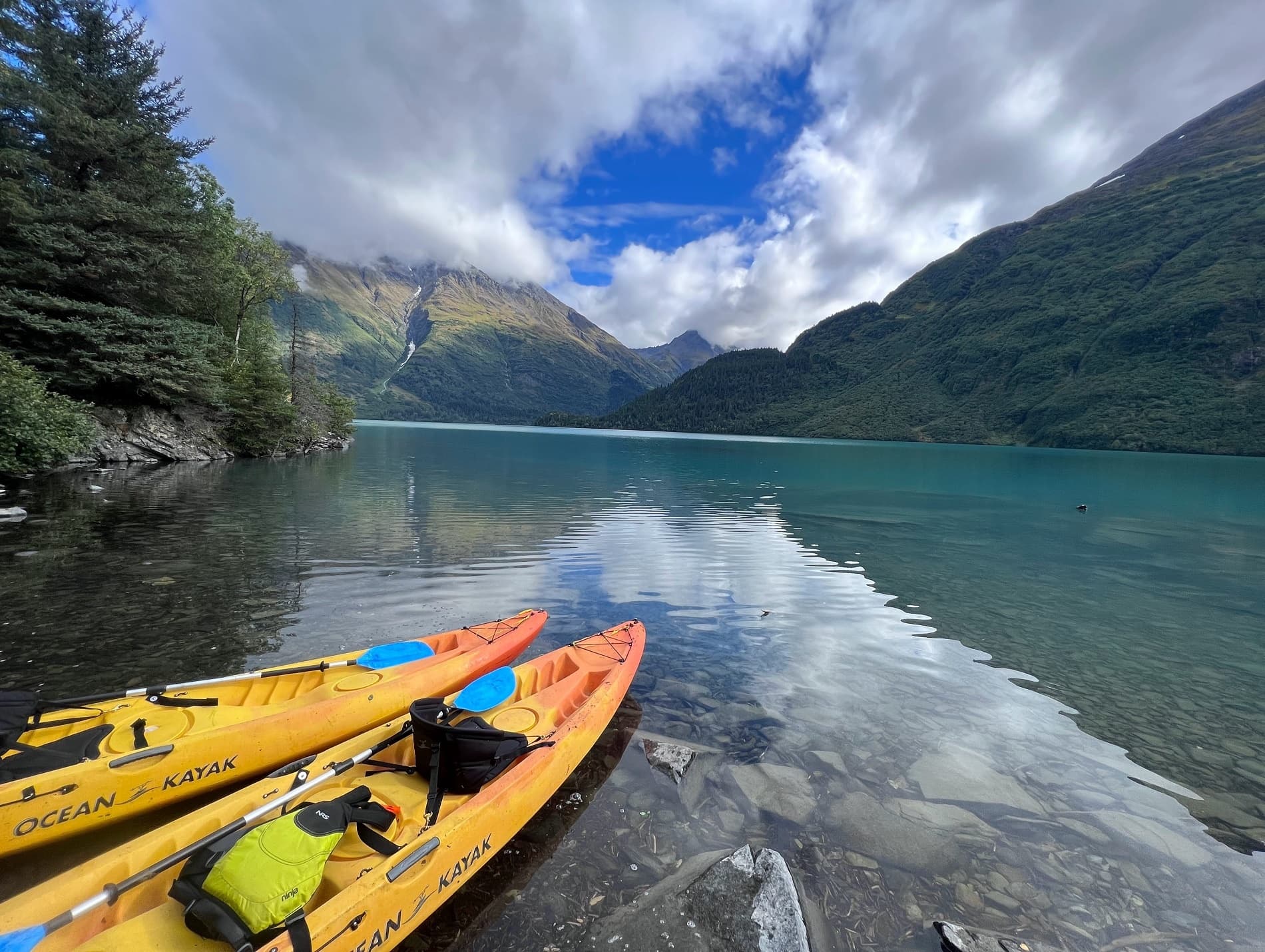 Colorful kayaks moored on reflective alpine lake shore