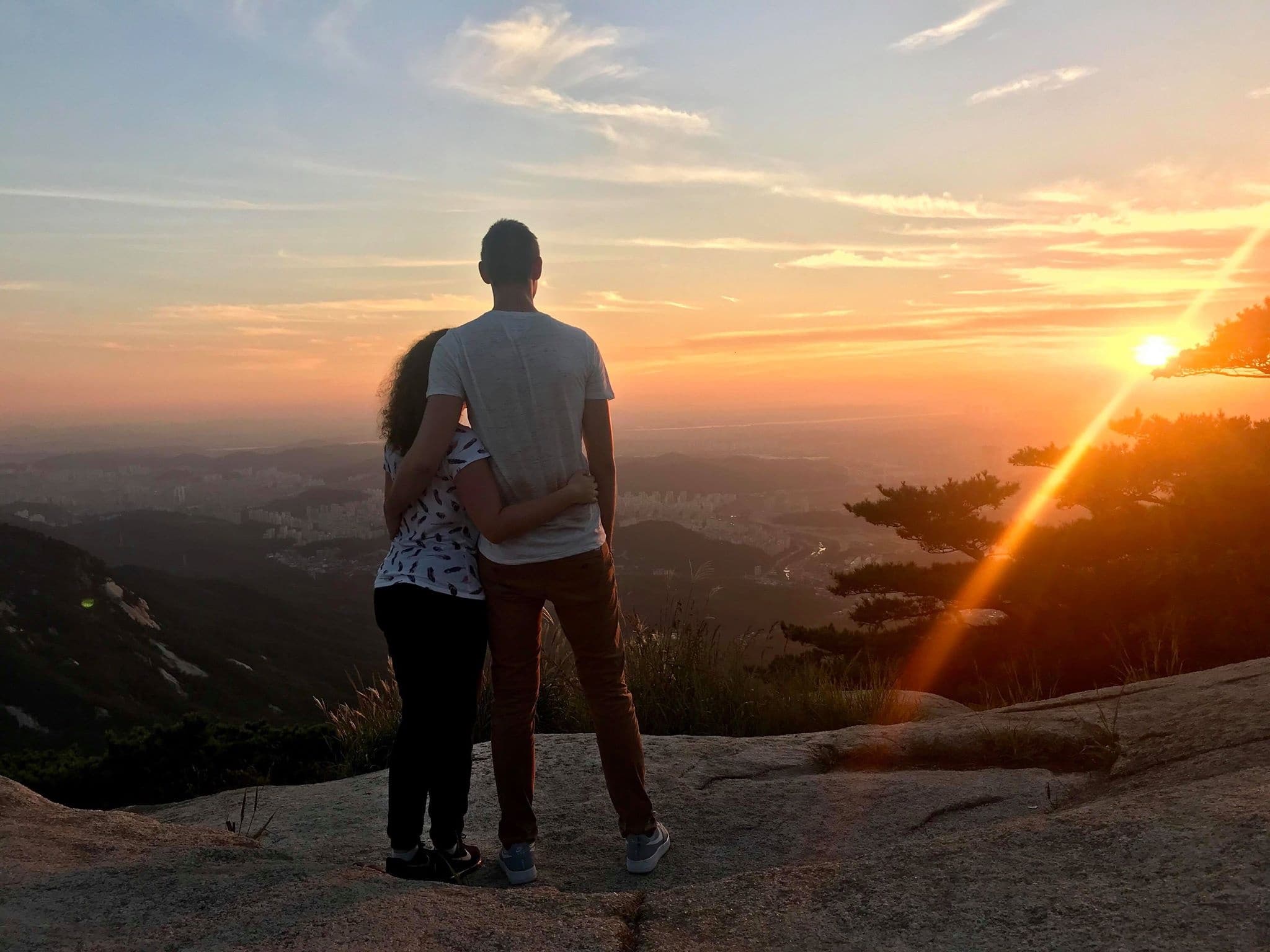 Couple watching sunset over mountain ridge at scenic viewpoint