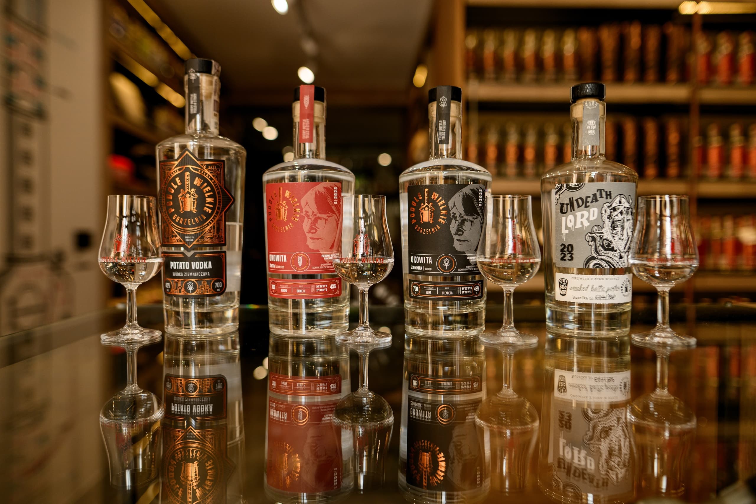 Lineup of craft spirit bottles and tasting glasses on reflective bar