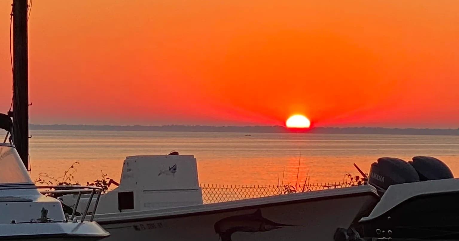 Sunset over marina with boats docked viewing orange horizon