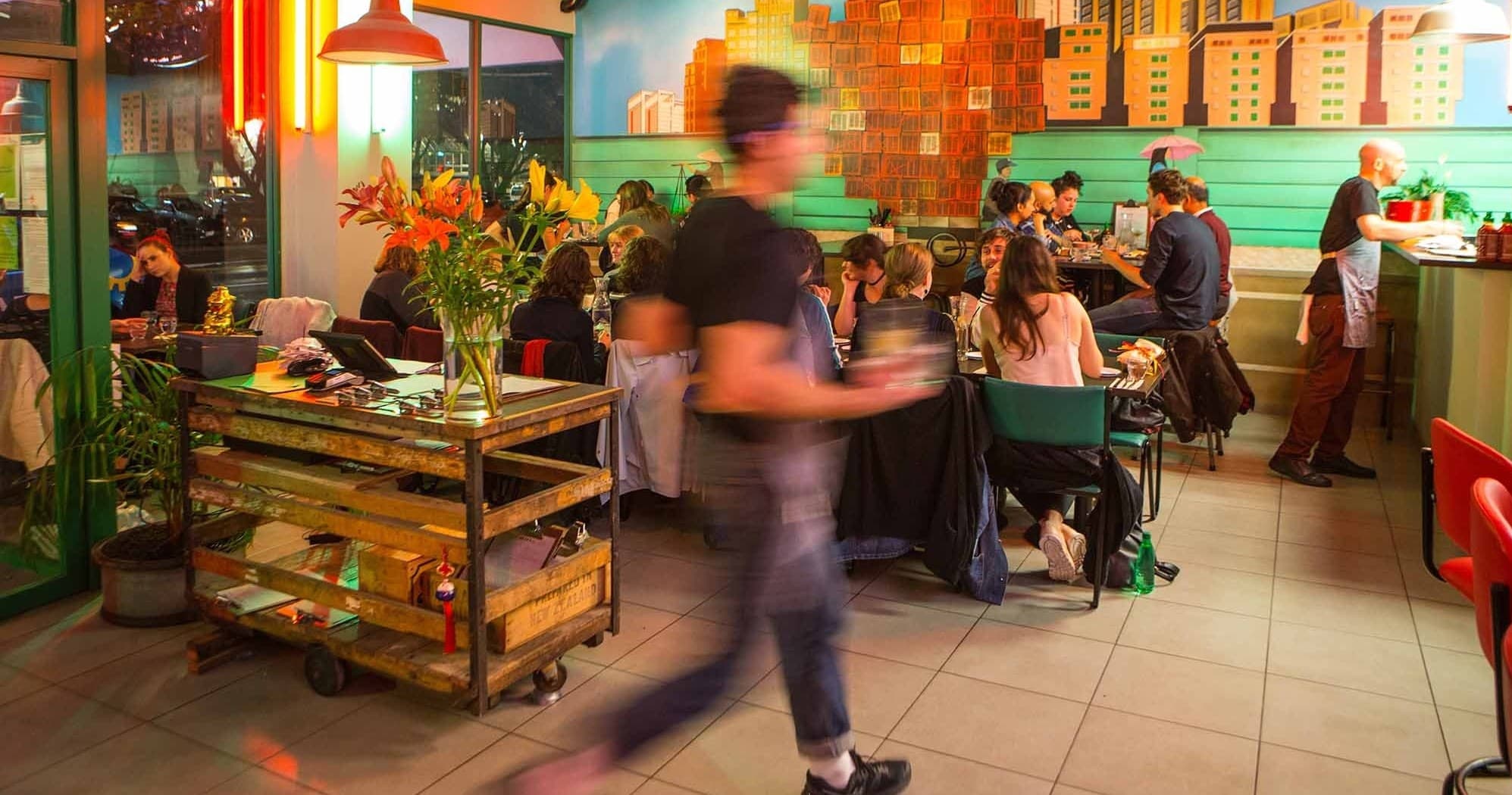 Busy colorful indoor restaurant with diners and servers moving