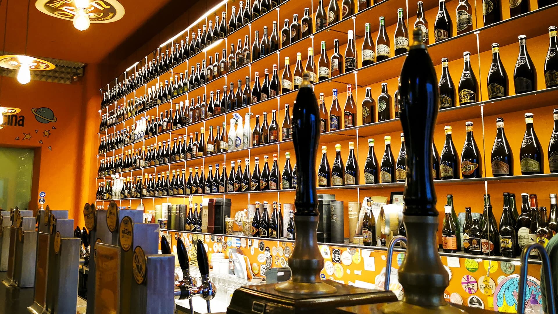 Craft beer taps and bottle wall in vibrant indoor bar setting