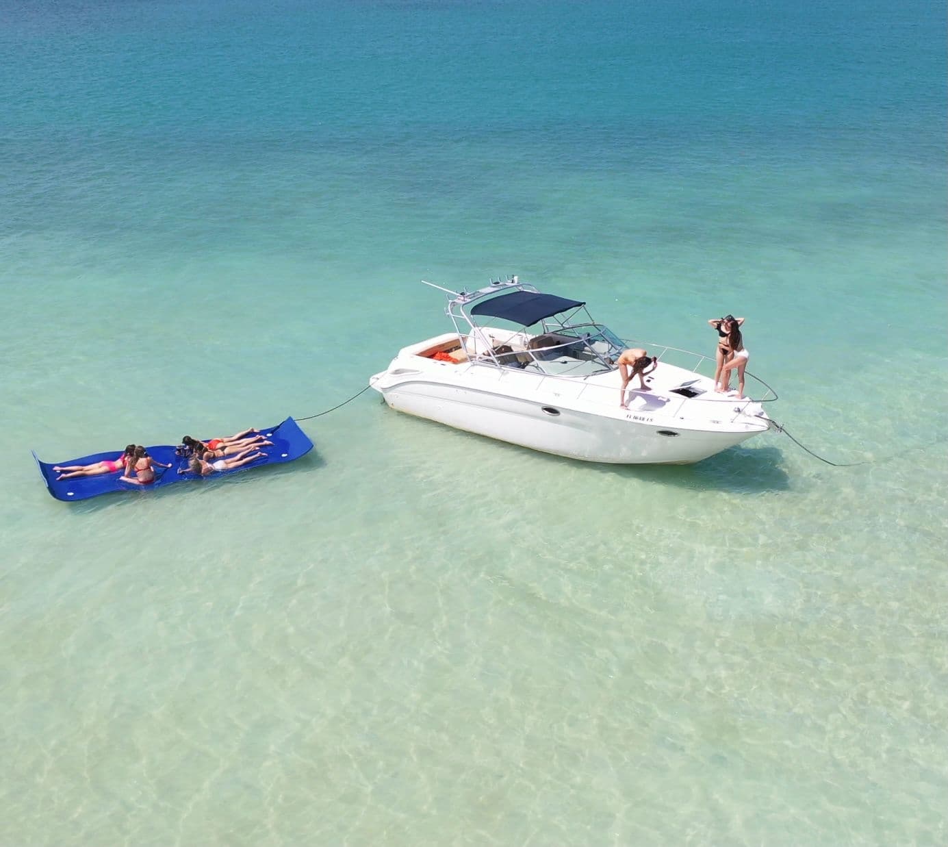 Motorboat anchored in clear shallow turquoise water with swimmers
