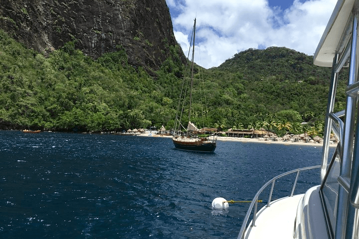 Boat cruising in Caribbean bay with lush volcanic mountains