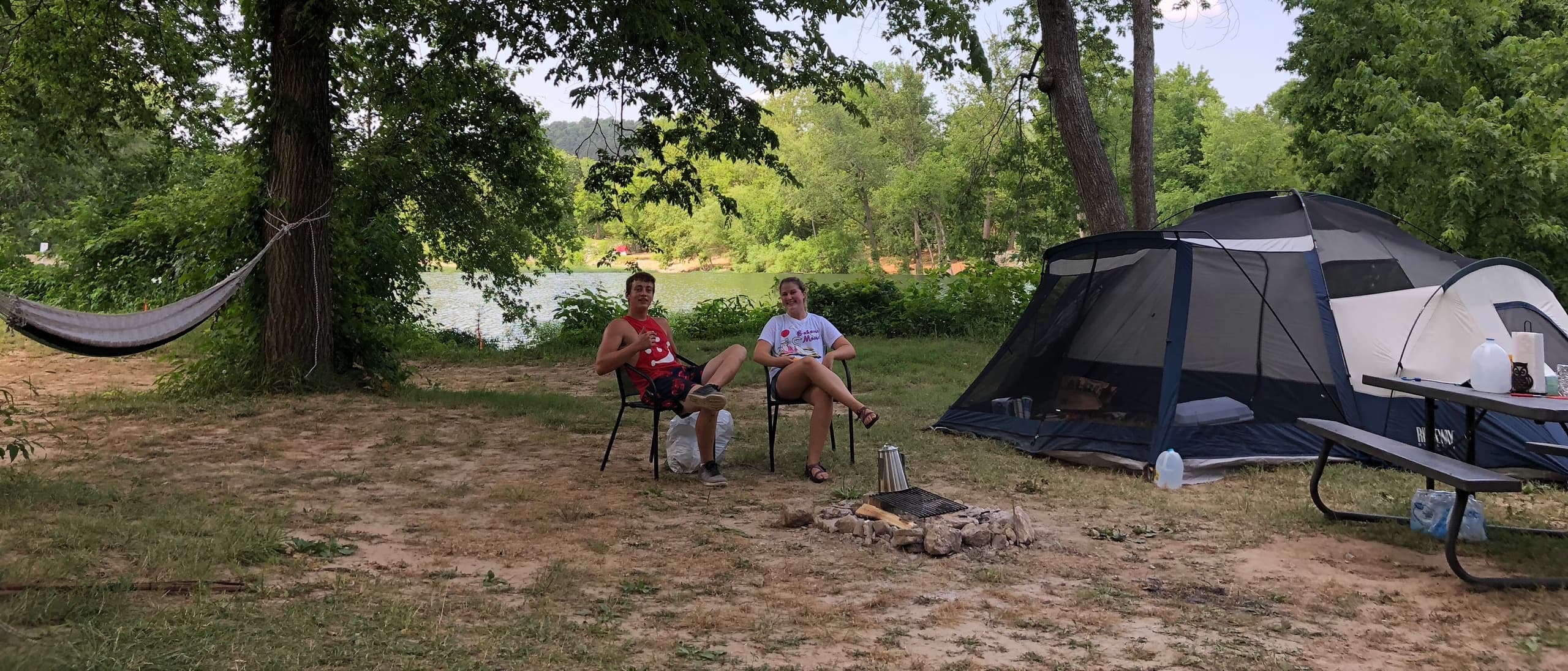Campers relaxing by tent and river at trestle park campsite