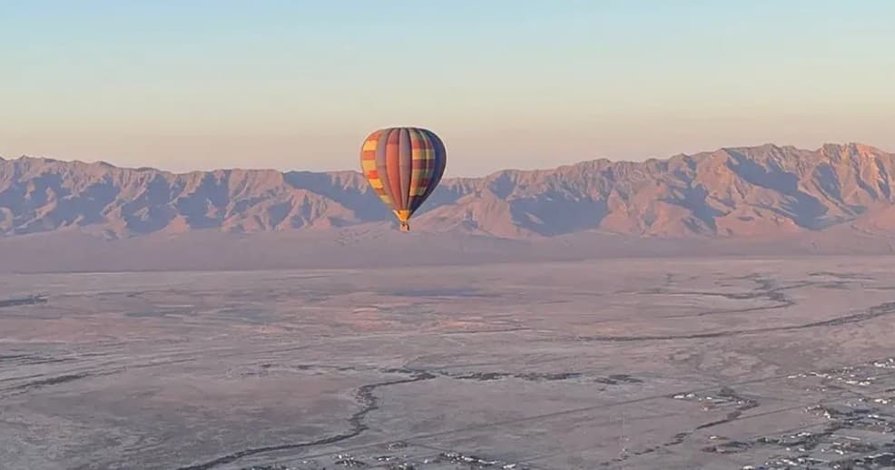 Hot air balloon floating over Nevada desert and mountain sunrise vista