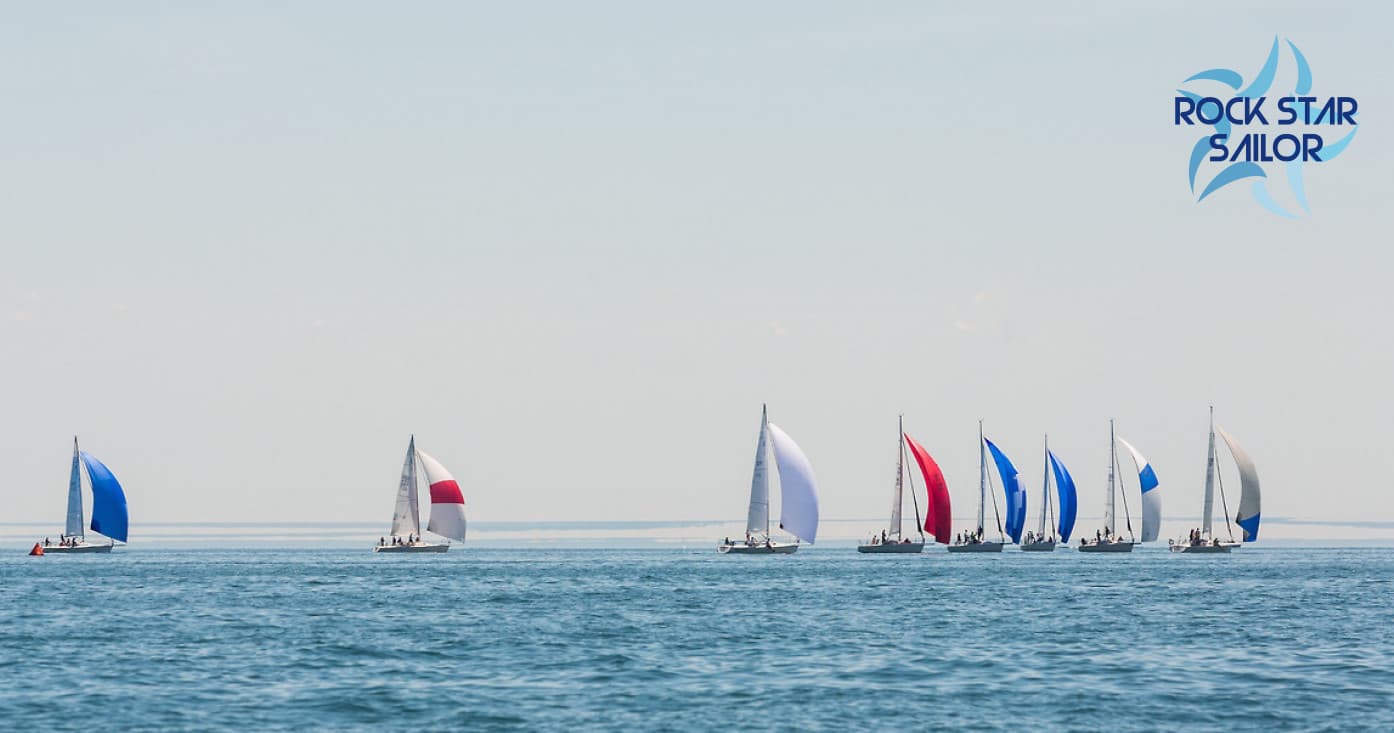 Fleet of colorful sailboats racing on calm ocean horizon