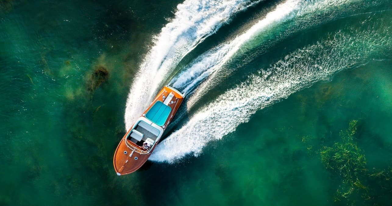 High-speed wooden motorboat carving a wake on Lake Como
