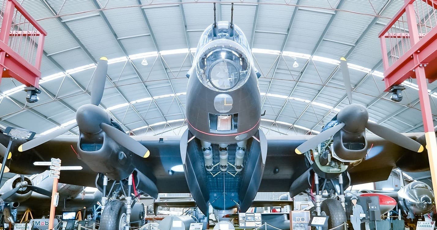 Historic bomber nose in museum hangar, polished fuselage display