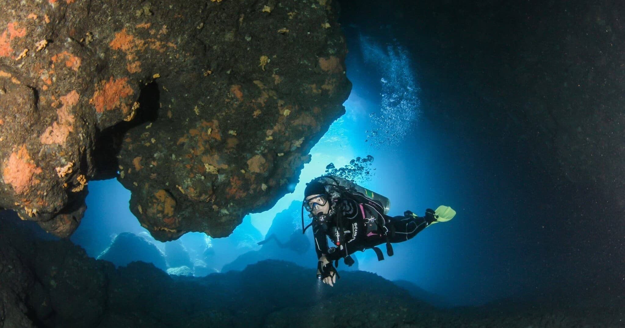 Diver exploring underwater rock arch and cave entrance