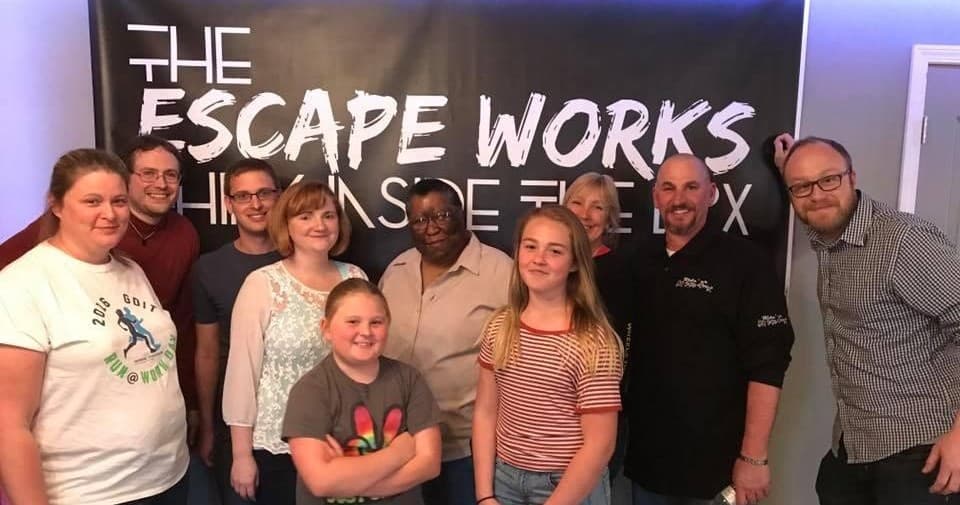 Escape room group posing under The Escape Works banner