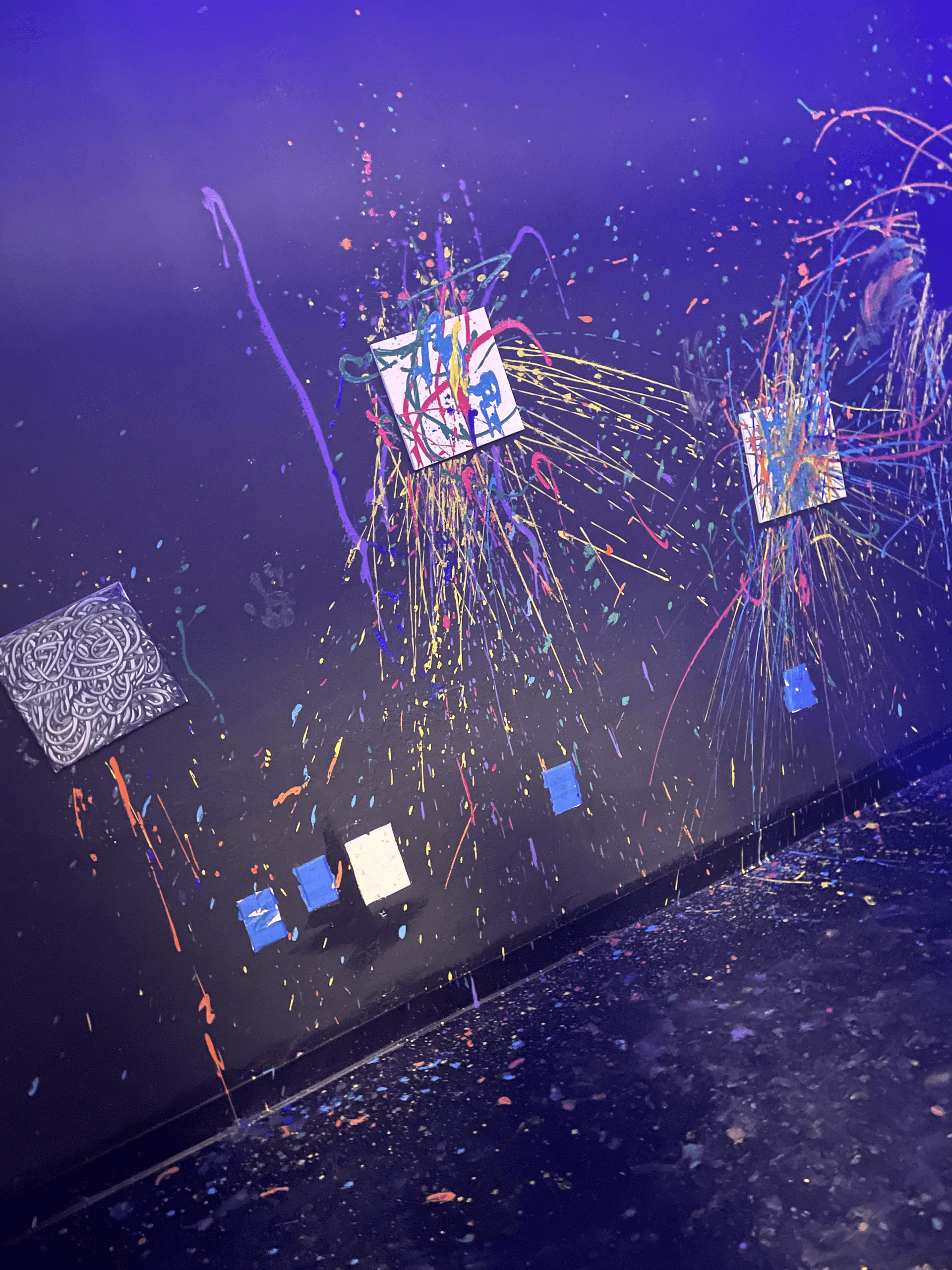 Blacklight splatter art wall in indoor paint rage room