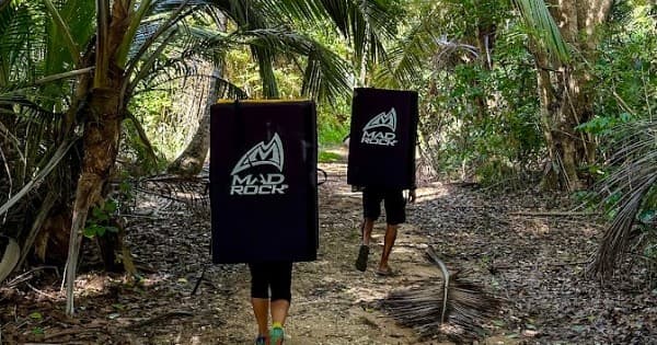 Bouldering approach carrying crash pads through tropical forest trail